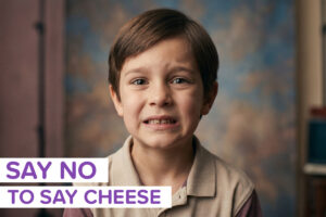 A kit struggling to smile naturally for a photo, with the label "say no to say cheese"